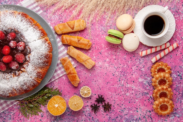 Foto gratuita vista superior delicioso pastel de fresa azúcar en polvo con taza de té macarons franceses y bagels en pastel de escritorio rosa galletas dulces de azúcar de galleta