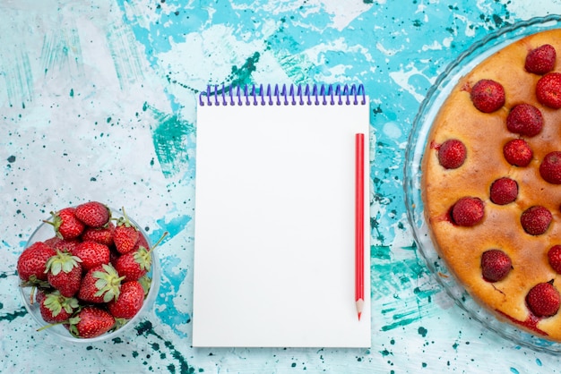 Vista superior delicioso pastel de fresa con frutas y junto con fresas rojas frescas y bloc de notas en el escritorio azul brillante masa de pastel galleta dulce fruta baya