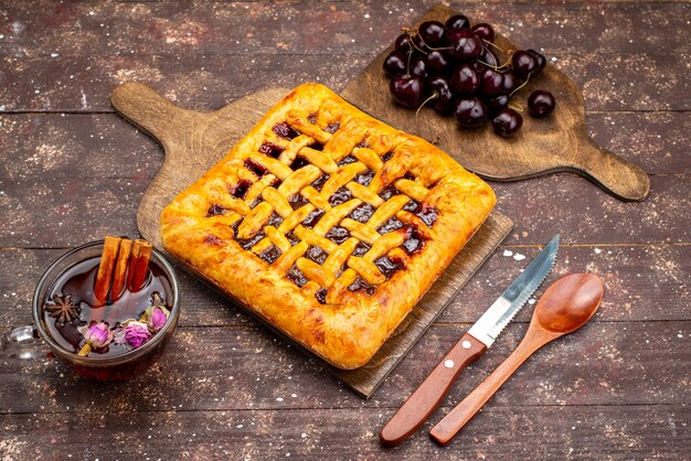Foto gratuita una vista superior del delicioso pastel de fresa con gelatina de fresa, cerezas y té en el escritorio de madera, pastel, galleta, azúcar