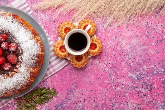 Vista superior delicioso pastel de fresa con taza de té y galletas sobre fondo rosa pastel galletas dulces galletas de azúcar