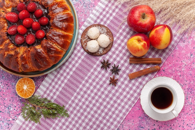 Vista superior delicioso pastel de fresa con taza de té en el rosa claro