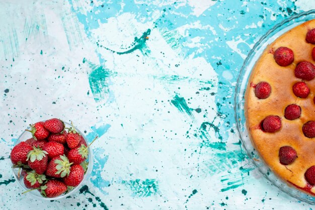 Vista superior delicioso pastel de fresas con frutas y junto con fresas rojas frescas en el escritorio azul brillante masa de pastel galleta dulce fruta baya