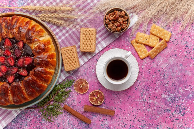 Vista superior del delicioso pastel de fresas con sabor a fruta con waffles y taza de té en rosa