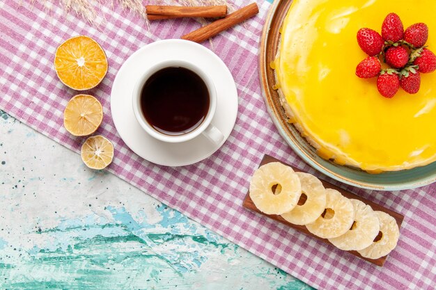 Vista superior delicioso pastel con jarabe amarillo taza de té y fresas frescas en superficie azul claro pastel de galletas pastel dulce galletas azúcar té