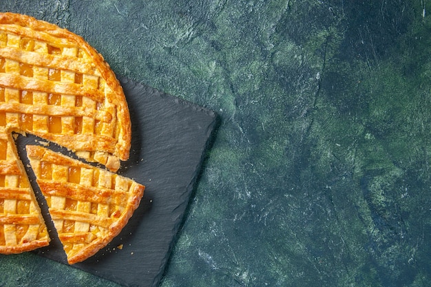 Vista superior del delicioso pastel de kumquat con una pieza en rodajas sobre una superficie oscura