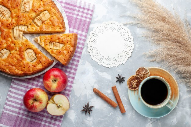 Vista superior del delicioso pastel de manzana dentro de la placa con manzanas y una taza de té en el fondo claro pastel pastel de galletas dulce