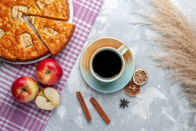 Vista superior delicioso pastel de manzana dentro de la placa con manzanas y una taza de té en la mesa de luz pastel de galletas dulces