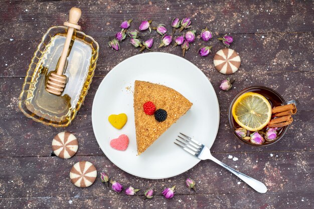 Una vista superior del delicioso pastel de miel con dulces de miel y flores sobre el fondo oscuro pastel de té dulces