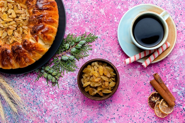 Vista superior del delicioso pastel de pasas con una taza de café sobre el fondo rosa pastel de hornear azúcar galleta dulce color de galleta