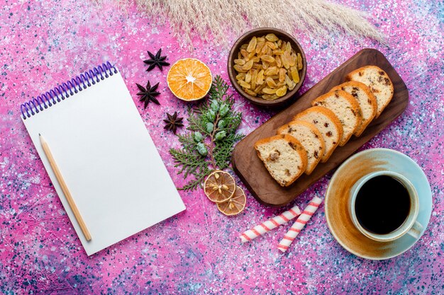 Vista superior del delicioso pastel en rodajas con pasas y con una taza de café en el escritorio de color rosa claro hornear pastel de azúcar galleta dulce galleta