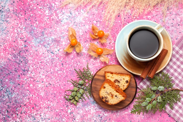 Vista superior del delicioso pastel en rodajas con una taza de té y canela en la superficie rosa