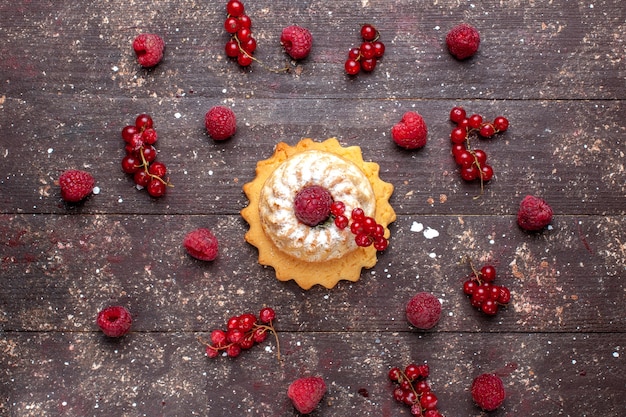 Vista superior del delicioso pastelito con azúcar en polvo junto con frambuesas y arándanos a lo largo de la galleta de pastel de frutas baya marrón