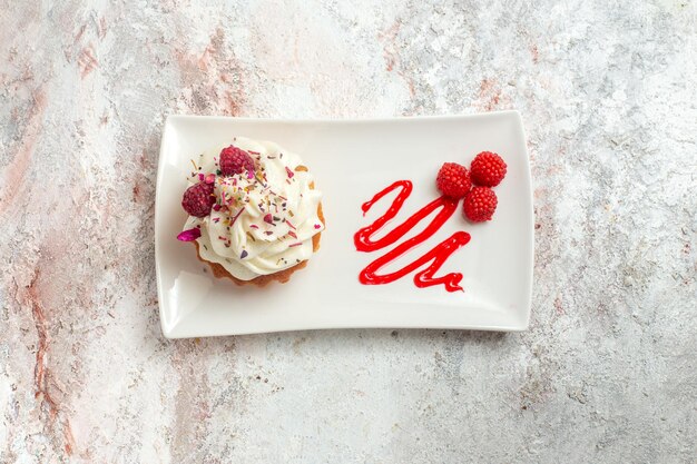 Vista superior delicioso pastelito con crema y frambuesas sobre fondo blanco pastel de té postre crema dulce galleta