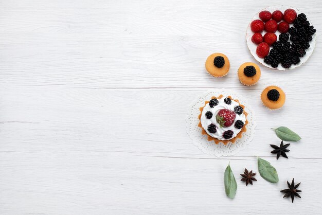 Vista superior del delicioso pastelito con crema y galletas de bayas en blanco, bizcocho de bizcocho hornear fruta dulce baya de azúcar