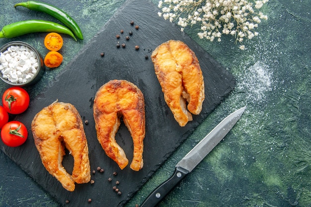 Vista superior delicioso pescado frito en un plato de superficie oscura ensalada freír carne pimiento de mar comida cocinar comida mariscos