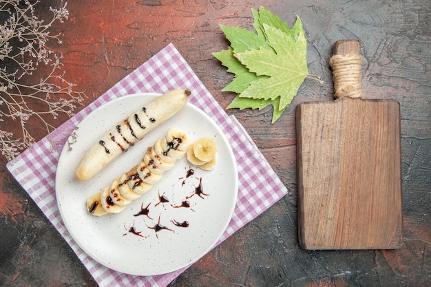 Vista superior delicioso plátano con trozos en rodajas sobre fondo oscuro