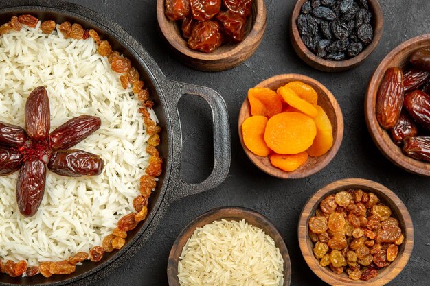 Vista superior delicioso plato de arroz cocido plov con diferentes pasas sobre fondo oscuro aceite de cena de arroz con pasas plato seco de frutas del este