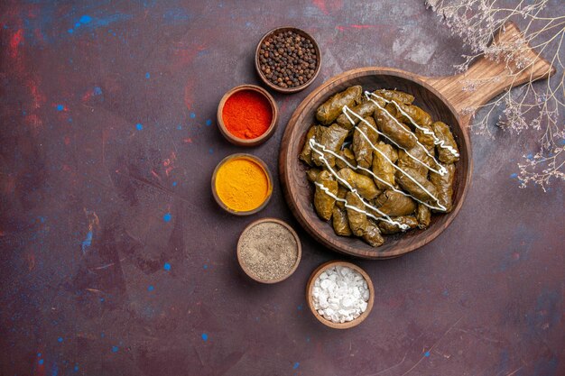 Vista superior del delicioso plato de carne de dolma con diferentes condimentos en el fondo oscuro comida calórica cena plato carne