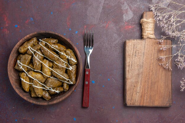 Vista superior del delicioso plato de carne oriental de dolma con hojas y carne molida en un escritorio oscuro comida calórica cena plato de aceite carne