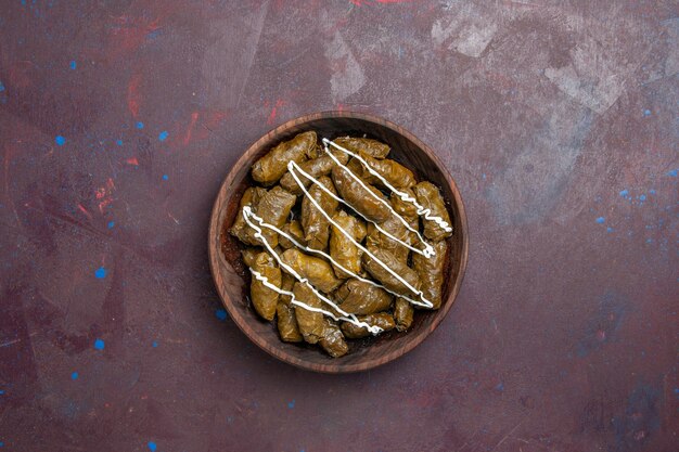 Vista superior del delicioso plato oriental de dolma con hojas y carne molida en el interior sobre un fondo oscuro, aceite, calorías, cena, carne, comida