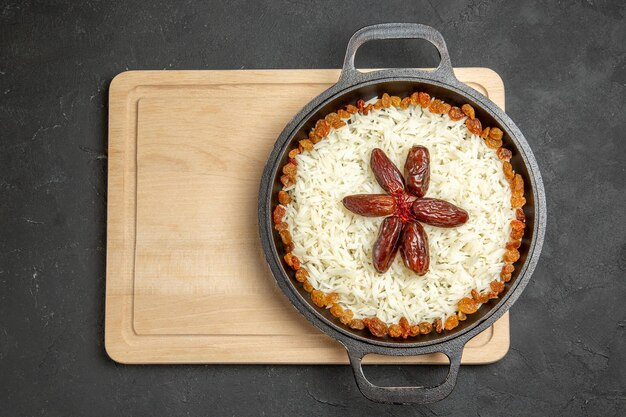 Vista superior delicioso plov plato de arroz cocido con pasas sobre fondo oscuro plato de pasas arroz cena aceite comida