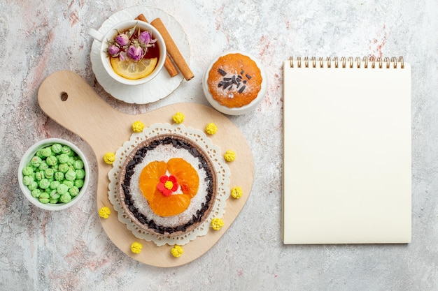 Foto gratuita vista superior del delicioso postre de chocolate con una taza de té sobre el fondo blanco pastel de galletas de crema postre de frutas