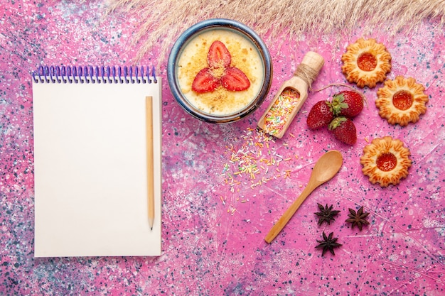 Foto gratuita vista superior delicioso postre cremoso con bloc de notas de fresas en rodajas rojas y pequeñas galletas sobre fondo rosa claro postre helado baya crema fruta dulce