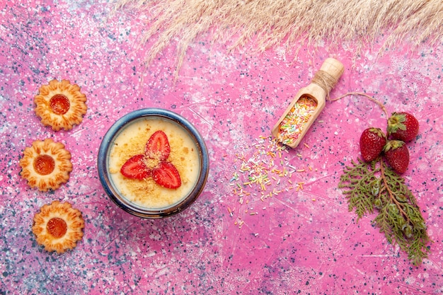 Vista superior delicioso postre cremoso con fresas en rodajas rojas y galletas en el fondo rosa claro postre helado baya crema fruta dulce