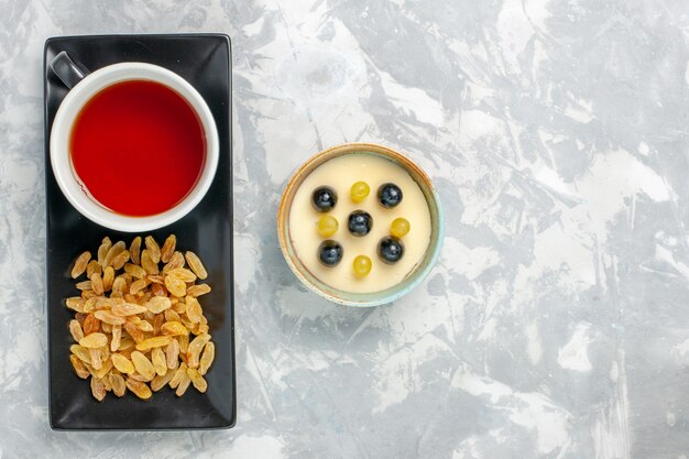 Vista superior delicioso postre cremoso con taza de té y pasas en superficie blanca postre crema de frutas helado helado dulce