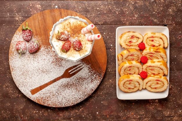 Vista superior del delicioso postre de fresa con rollos de frutas dulces en el escritorio de madera marrón