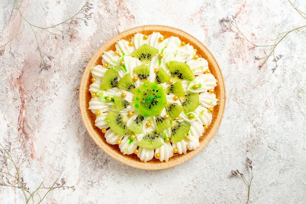 Vista superior delicioso postre de kiwi con deliciosa crema blanca y frutas en rodajas sobre fondo blanco postre pastel crema fruta tropical