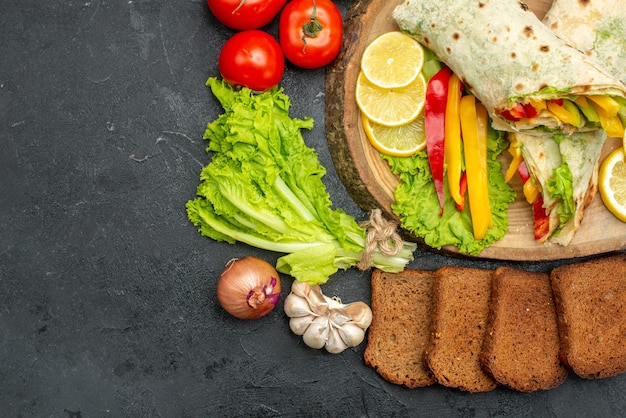 Vista superior del delicioso sándwich de carne shaurma en rodajas con pan y verduras en gris negro