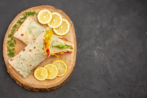 Vista superior del delicioso sándwich de carne shaurma en rodajas con rodajas de limón en negro