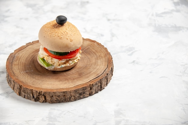 Vista superior del delicioso sándwich casero con aceituna negra en la tabla de cortar de madera en el lado derecho sobre la superficie blanca manchada