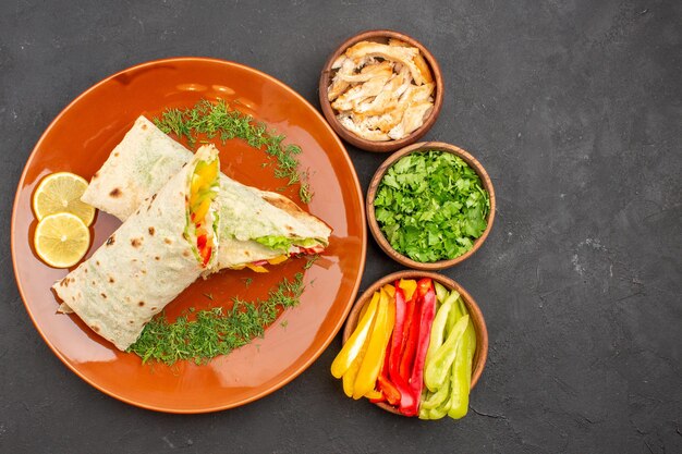 Vista superior delicioso sándwich de ensalada shaurma en rodajas dentro de la placa en el escritorio oscuro bocadillo de pan sándwich de comida de hamburguesa