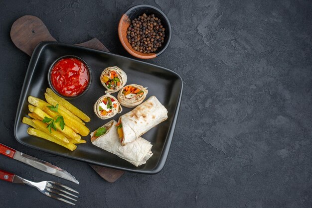 Vista superior delicioso sándwich de pita en rodajas de shaurma con papas fritas y salsa de tomate en la superficie oscura hamburguesas comida bocadillo pan comida rápida comida tostada parrilla