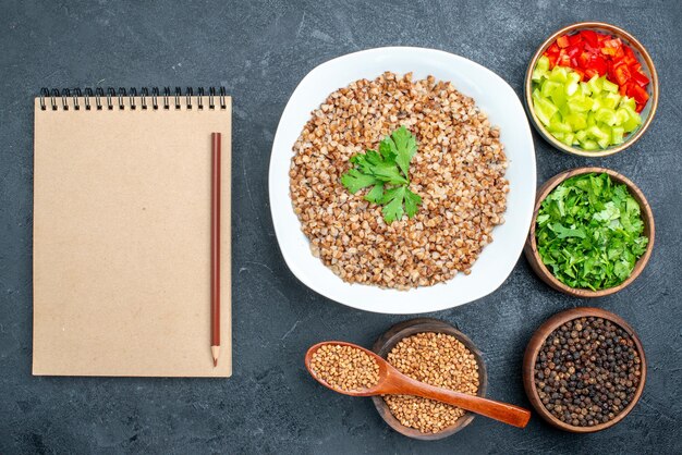 Vista superior del delicioso trigo sarraceno cocido con verduras en el escritorio gris