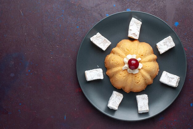 Vista superior del delicioso turrón de dulces de azúcar en polvo con pastel dentro de la placa sobre una superficie oscura