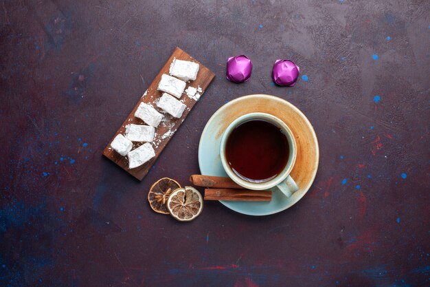 Vista superior del delicioso turrón de dulces de azúcar en polvo con té en la superficie oscura