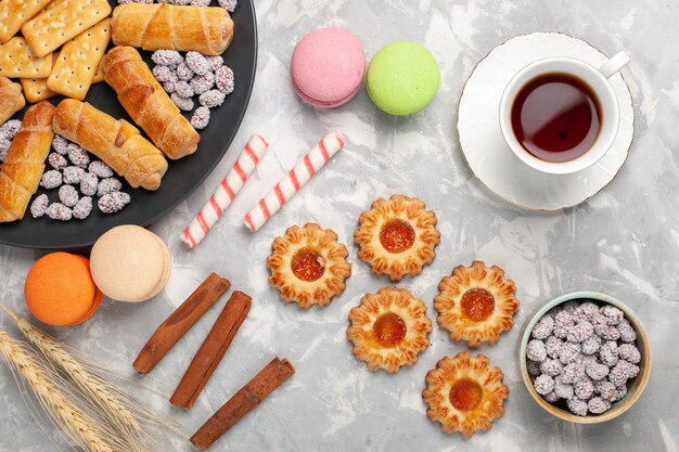 Vista superior deliciosos bagels con galletas macarons de canela y galletas en el escritorio blanco pastel biscuit pastel de azúcar dulce cookie crujiente