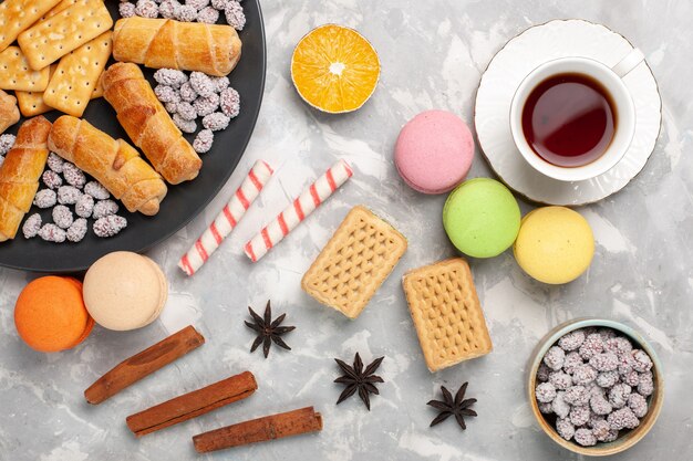 Vista superior deliciosos bagels con galletas waffles macarons y taza de té en el escritorio blanco pastel biscuit dulce pastel de azúcar cookie crujiente
