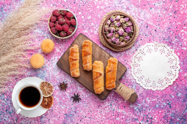 Vista superior de deliciosos bagels con taza de té en la superficie rosa