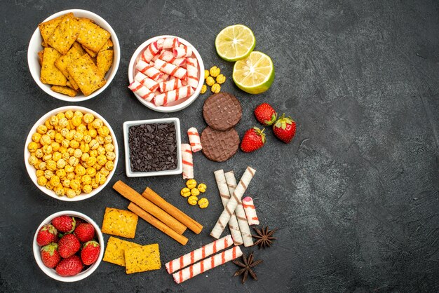 Vista superior deliciosos bocadillos con galletas trozos de chocalate rodajas de limón sobre fondo negro con espacio libre