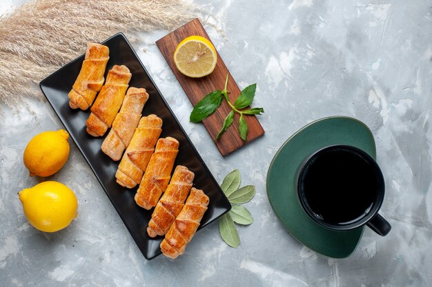 Vista superior deliciosos brazaletes dulces con limón y té en la mesa de luz, pastel de pastelería hornear azúcar dulce