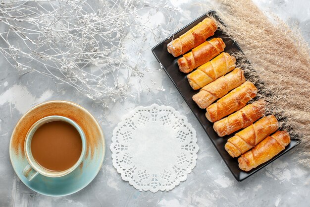 Vista superior de deliciosos brazaletes horneados dentro del molde negro con café con leche en gris, pastelería hornear pastel de galletas dulce