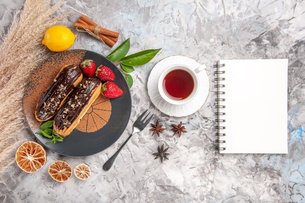 Vista superior deliciosos canutillos de chocolate con taza de té en una galleta de postre de pastel de galleta blanca