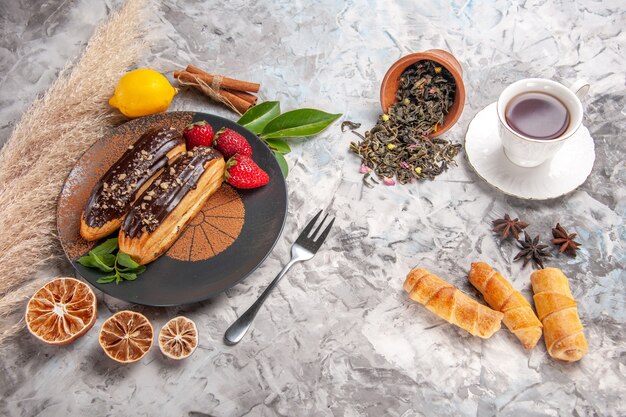 Vista superior deliciosos canutillos de chocolate con taza de té en una galleta de postre de pastel de galletas blancas