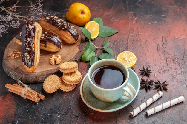 Vista superior deliciosos canutillos de chocolate con taza de té en el piso oscuro postre dulce pastel