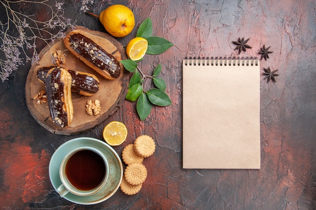 Vista superior deliciosos canutillos de chocolate con taza de té en el piso oscuro postre dulce pastel