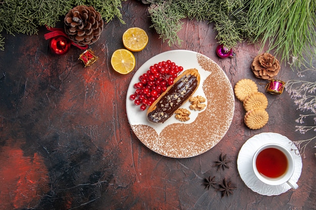Vista superior deliciosos canutillos de chocolate con té y bayas en el postre de pastel de pastel dulce de mesa oscura